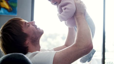 Cheerful-dad-holding-happy-baby-daughter